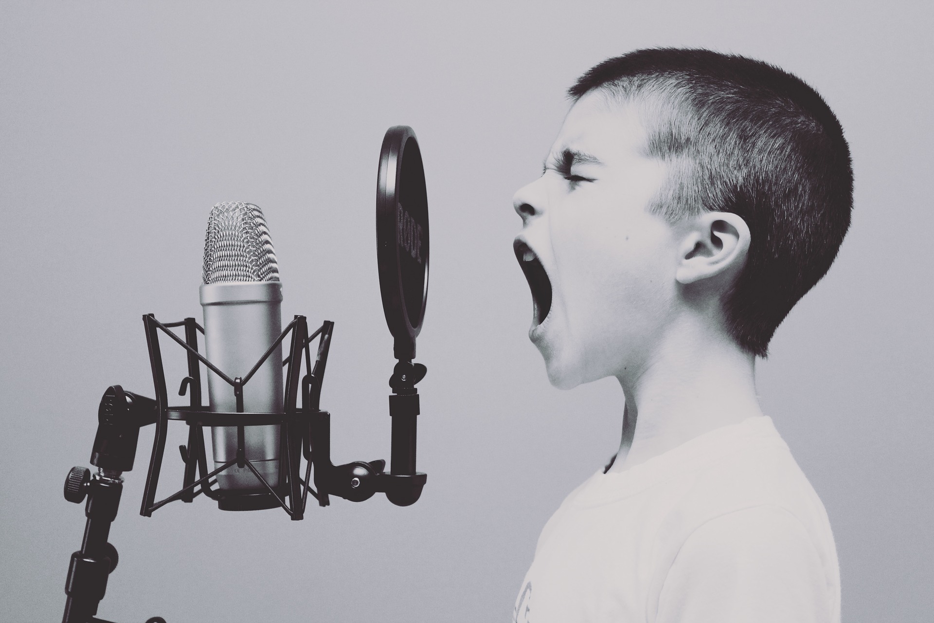 A boy is screaming into a microphone