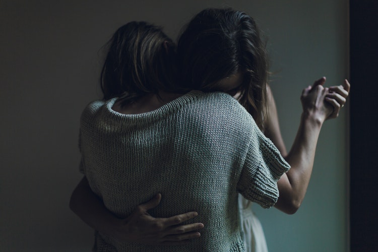 two people embrace in ballroom hold leaning their heads on each others shoulders.