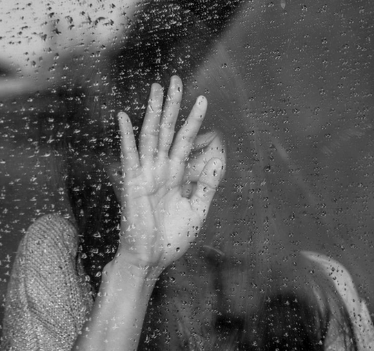 black and white picture of woman leaning her hand against a rainy window banner childhood abuse