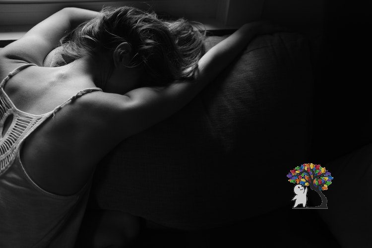 black and white photograph of a girl leaning her torso against a bed. her back is aimed at the camera