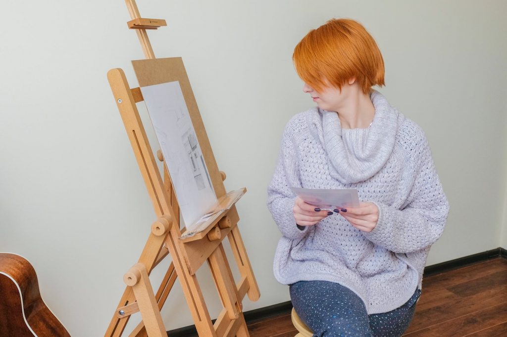 serious lady looking at sketch during painting in workshop
