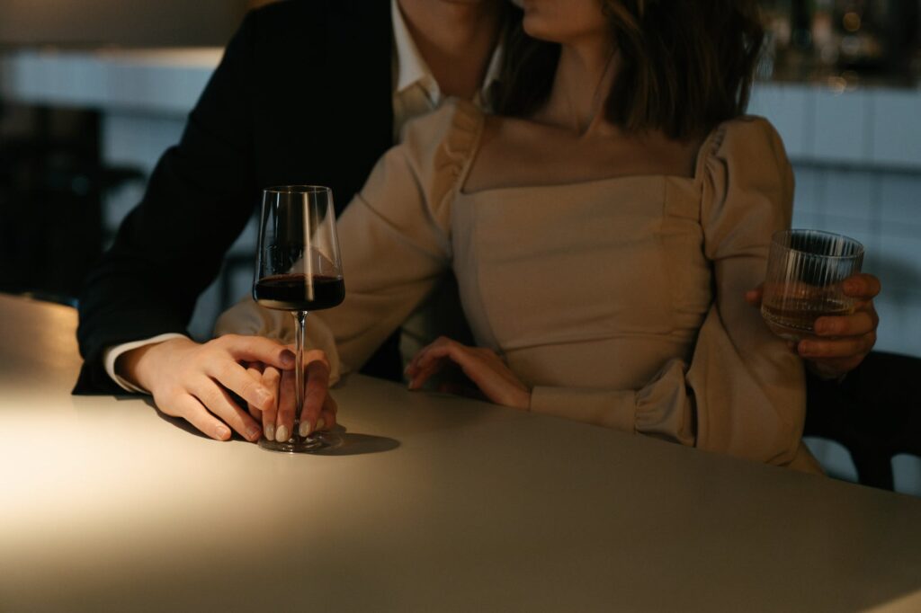 woman in beige long sleeve shirt holding wine glass