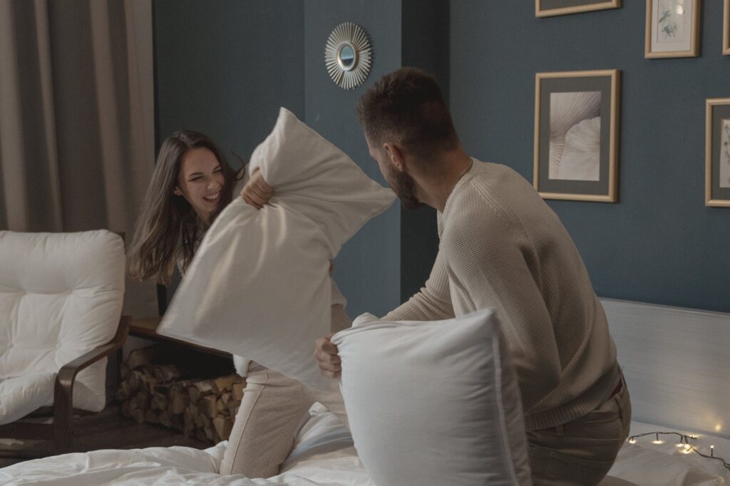 a couple having fun playing pillow fight