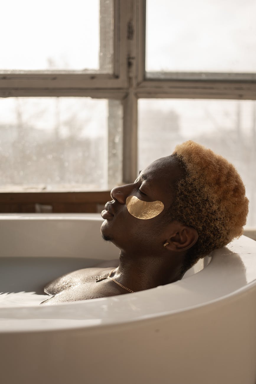 relaxed young black man taking bath with closed eyes