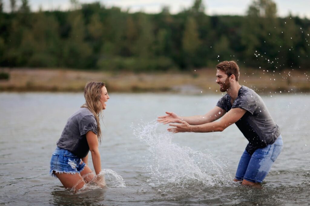 man and woman playing on body of water