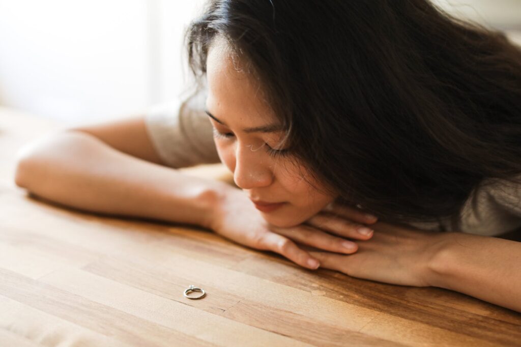 a woman crying near the wooden table while looking at the ring